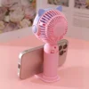 un pequeño ventilador que sirve además como soporte para celular en color rosado